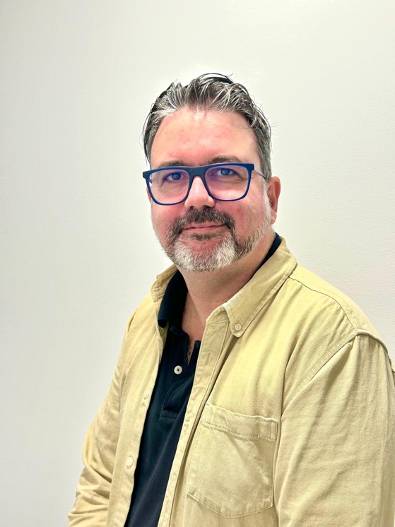 Un hombre con lentes y una camisa gris